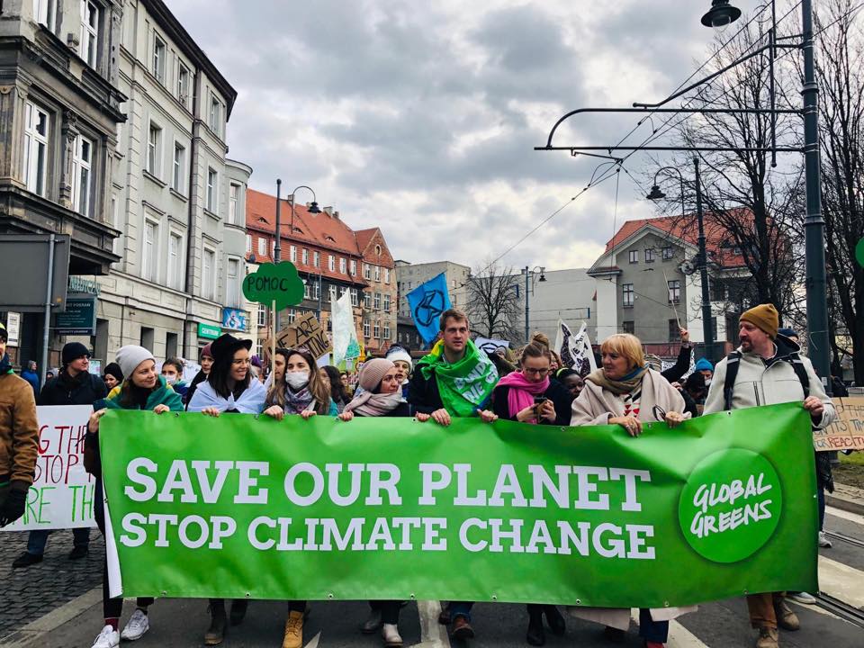 Grüne demonstrieren hinter dem Banner "Save our Planet, stop climate change"